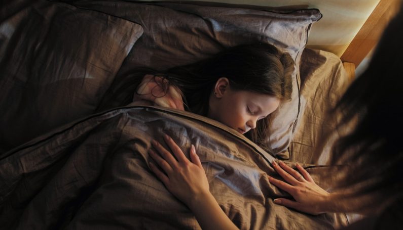 mother tucking sleeping child in for the night (bedtime story)