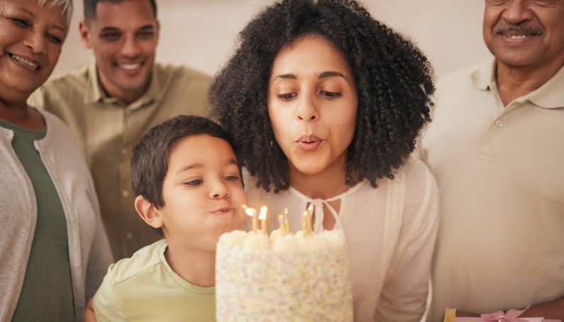 family celebrating birthday with woman and child blowing candles out, last year of 30s, turning 40