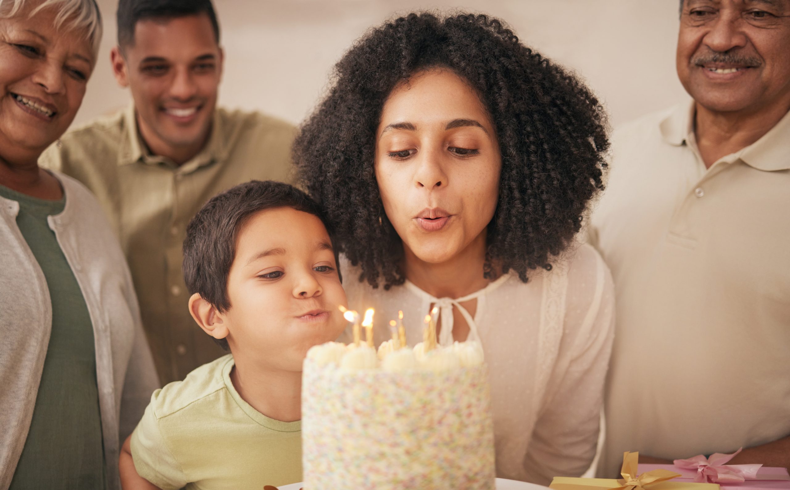 family celebrating birthday with woman and child blowing candles out, last year of 30s, turning 40