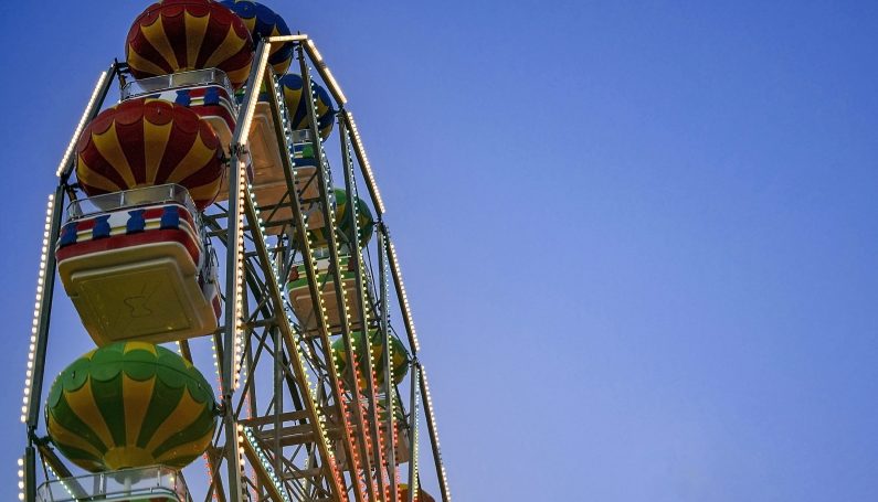 Large multi-colored ferris wheel against blue sky. Fall fairs and festivals in Boston.