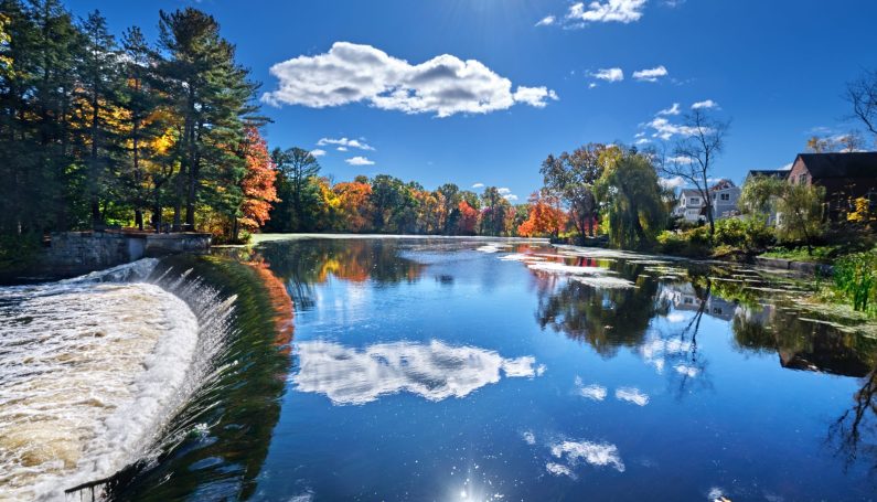 Weir on the Charles River and fall sunshine reflecting in the water at South Natick Dam Park (Natick Massachusetts)