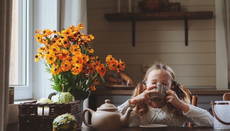 child sitting at table sipping mug of warm tea (herbal tea blends for kids)
