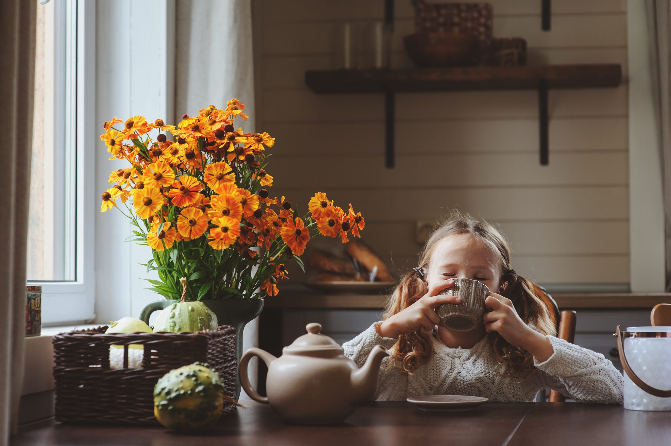 child sitting at table sipping mug of warm tea (herbal tea blends for kids)