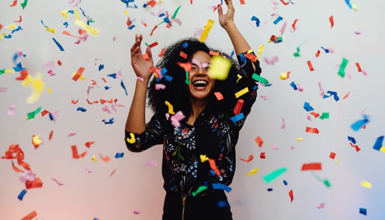 Young woman dancing under confetti celebrating birthday (baby free era, done having babies, 40s, 40th birthday)