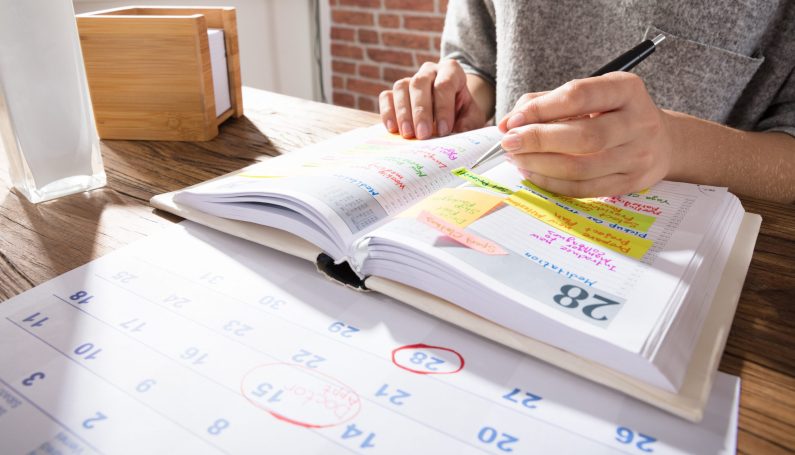 woman making schedule on calendar (volunteer fatigue and mom guilt)