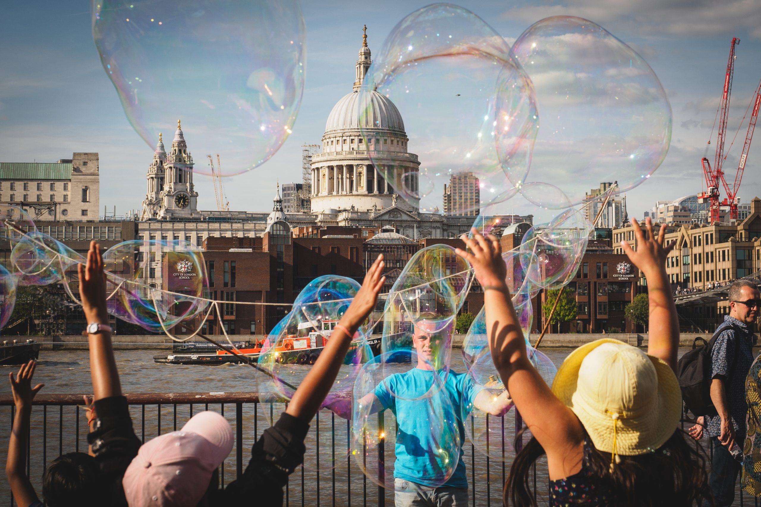 London, UK - March, 2018. Young kids having fun with soap bubbles made by a street performer on the South Bank of the Thames, with St. Paul's Cathedral in the background (Europe with kids)