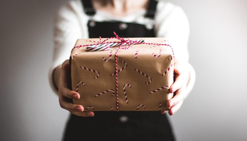 woman holding wrapped holiday package (holiday help for Boston families and children)