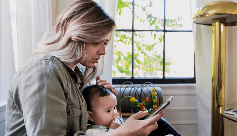 mom with young baby looking at social media on phone