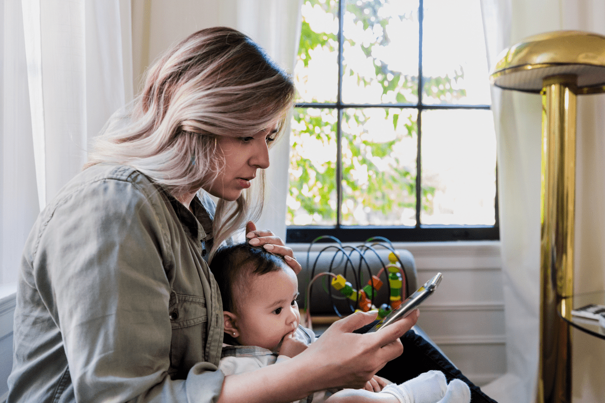 mom with young baby looking at social media on phone