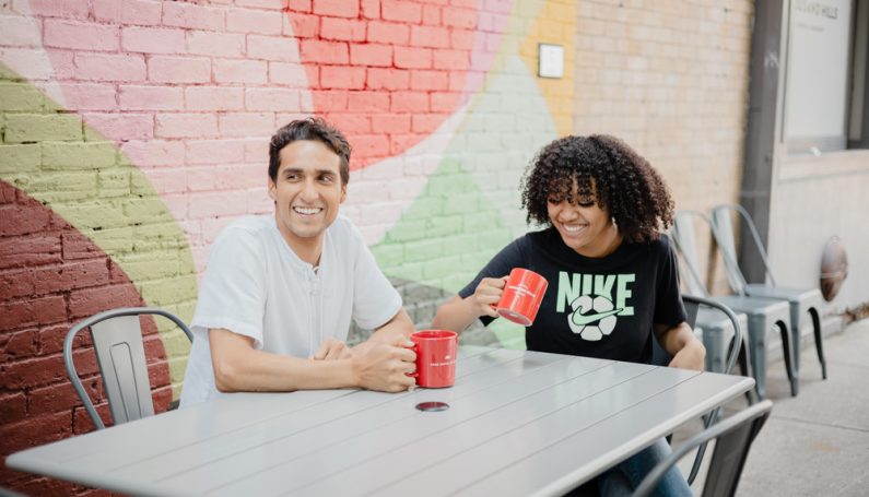 Two people sitting at a table, outside