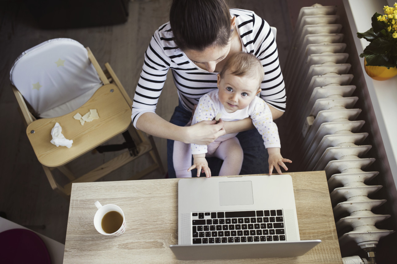 Young mother in home office with computer and her daugher
