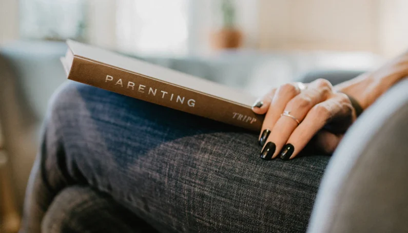 parenting book resting on a woman's lap