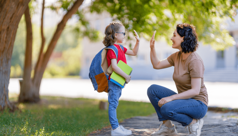 mom and child high-fiving after school (questions to ask your child after school)