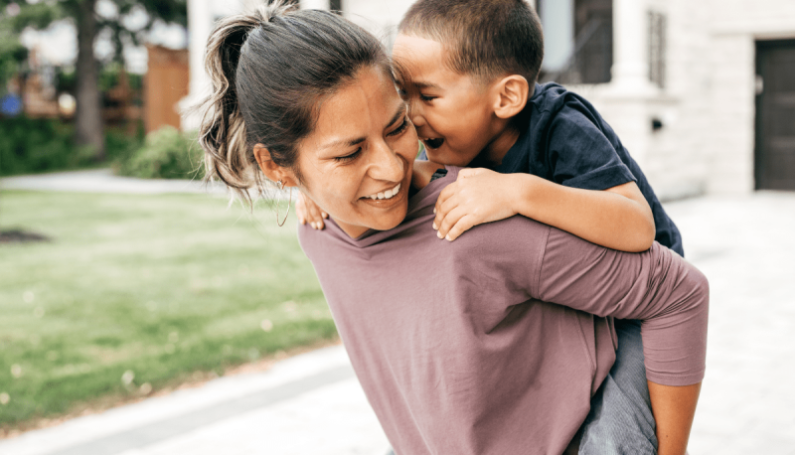 smiling mom carrying child piggy back