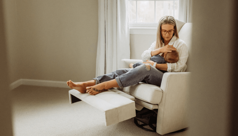 woman on recliner holding newborn (TV shows to binge watch with newborn)