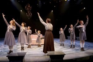 Production of “The Sound of Music.” Woman and children singing on stage.
