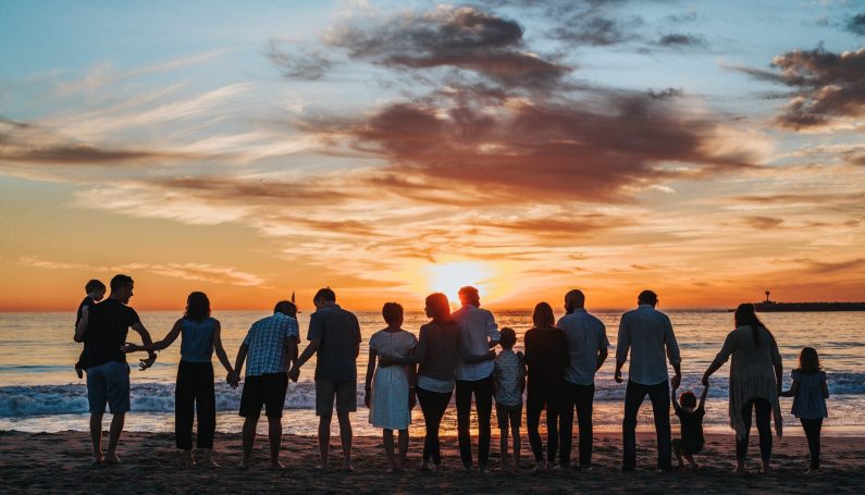large multi-generational family standing on the beach on vacation
